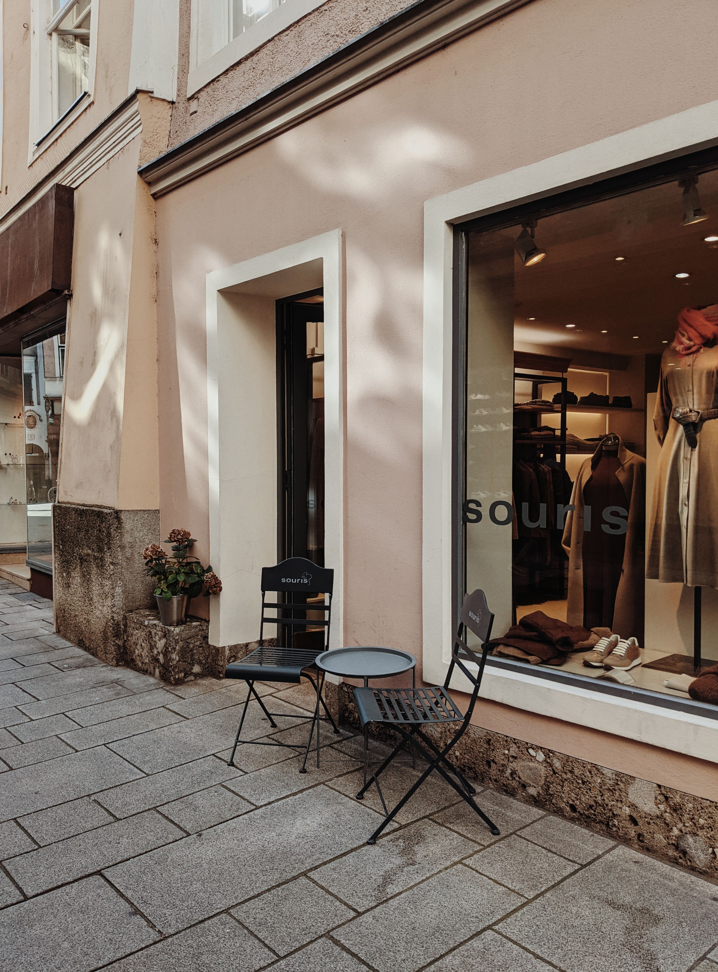 Street view of a boutique in Salzburg featuring stylish outdoor seating and window display.