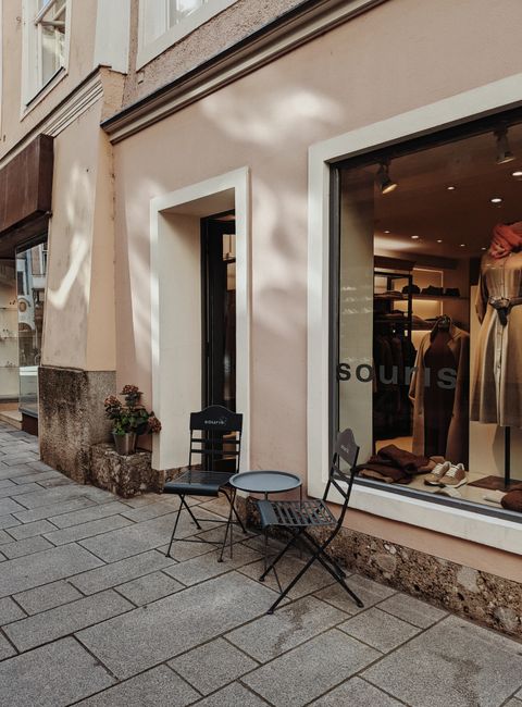 Street view of a boutique in Salzburg featuring stylish outdoor seating and window display.