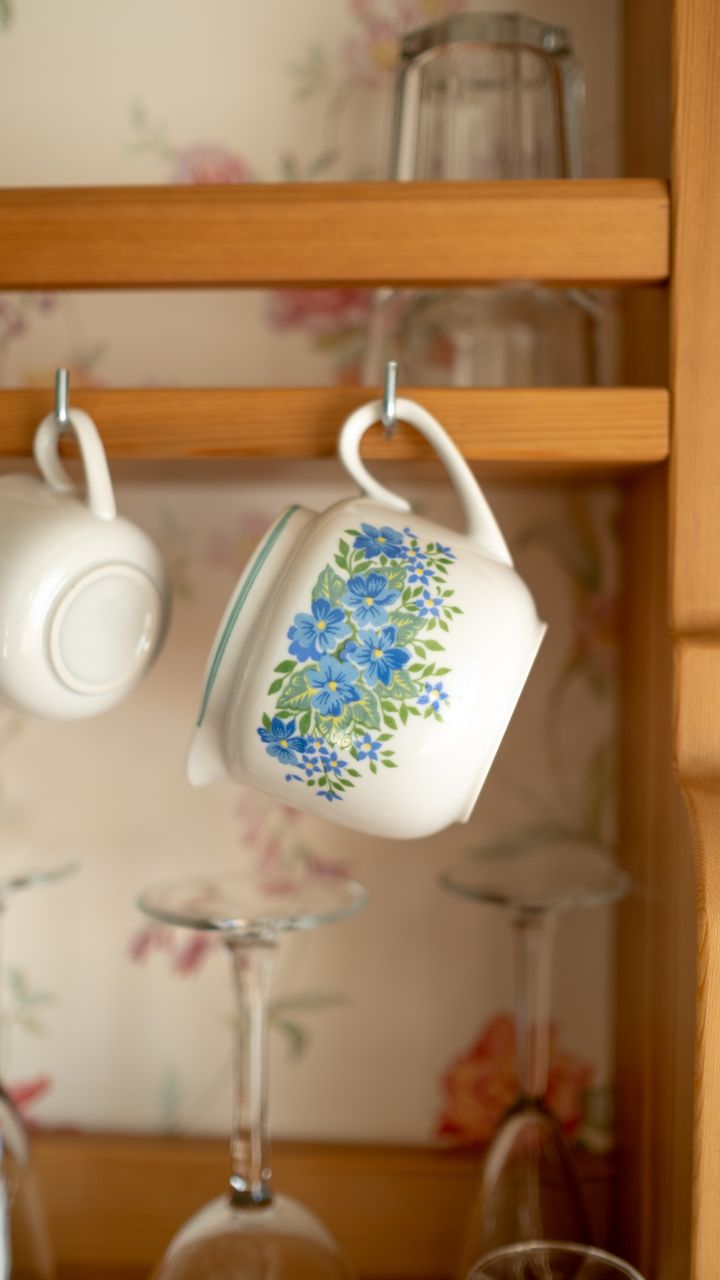 Wall-mounted command hooks holding colorful mugs for a dollar tree coffee bar design