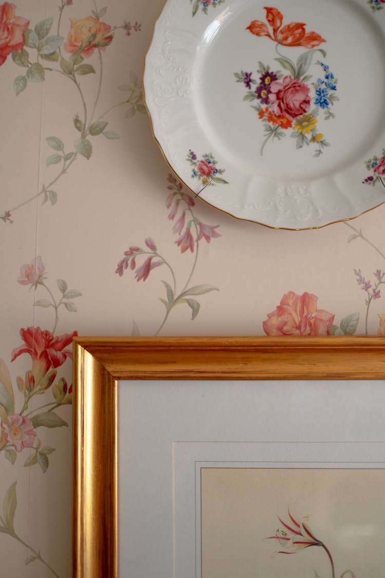 Vintage Plate And Picture Hanging On Wall Covered With Floral Wallpaper