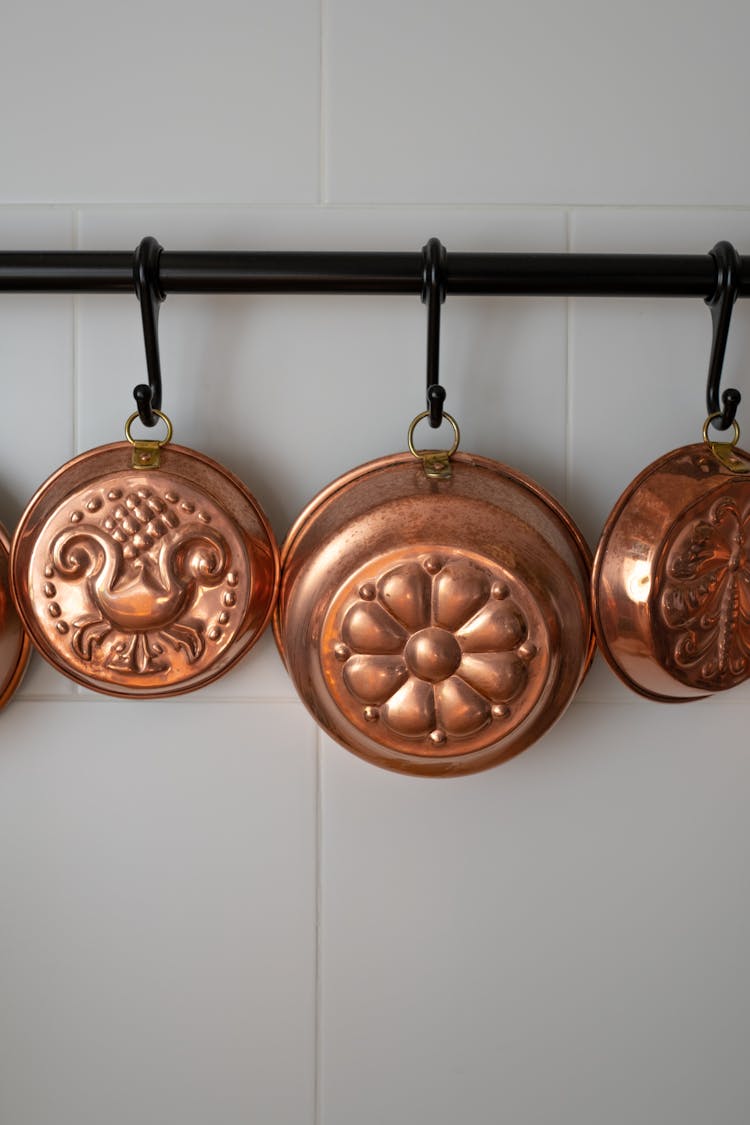Vintage Copper Baking Pans Hanging On Wall In Kitchen