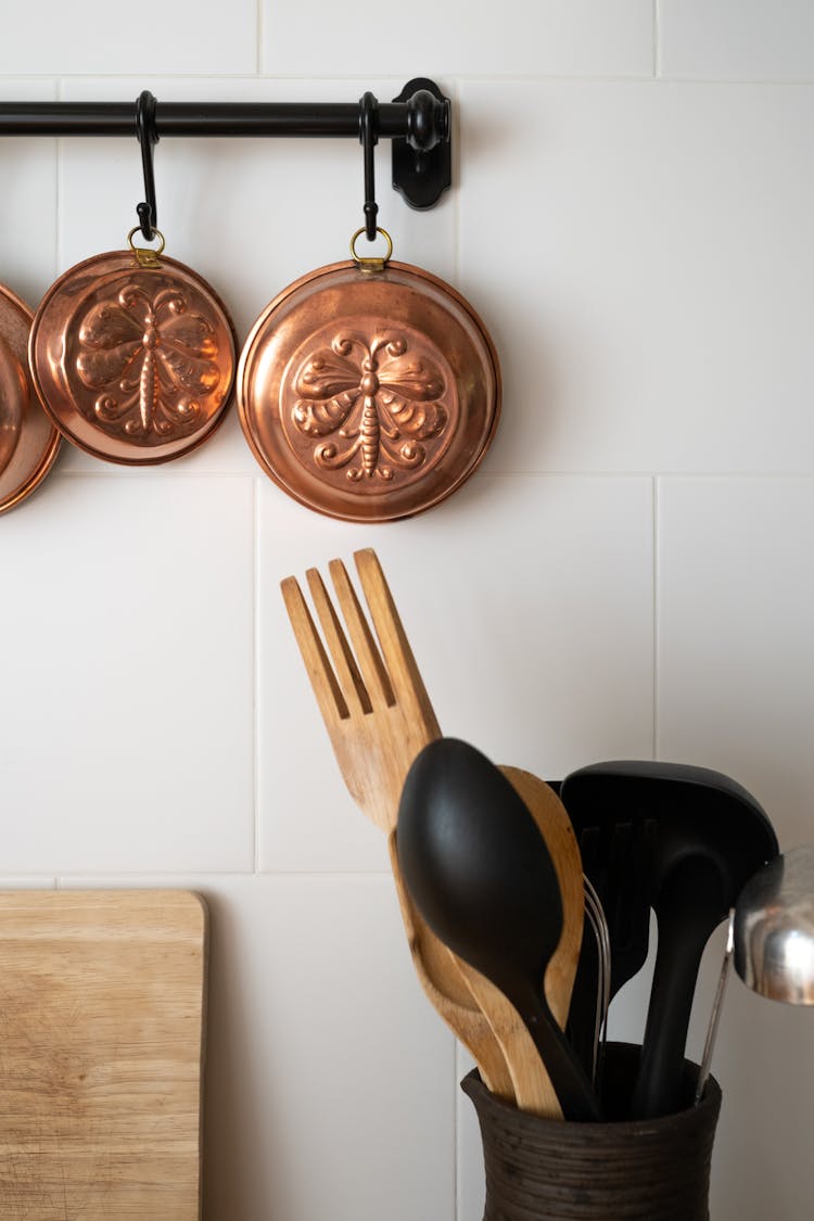 Old-Fashioned Copper Baking Pans Hanging On Wall In Kitchen