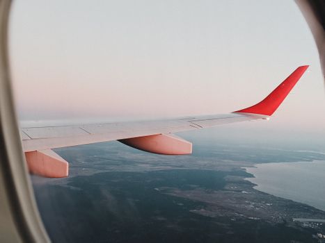 View from airplane window showing landscape of Vienna with sunset sky.