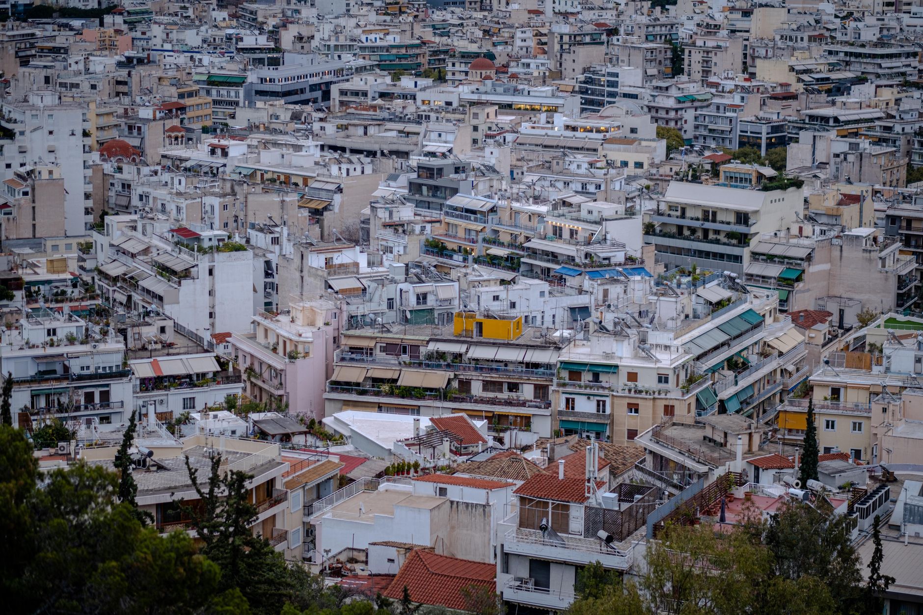 An aerial view showcasing the tightly packed buildings of Athens, Greece, featuring urban rooftops and diverse architecture.