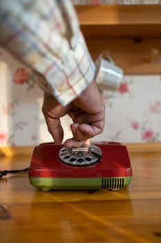 Close-up of a hand dialing a vintage rotary phone on a wooden table indoors.