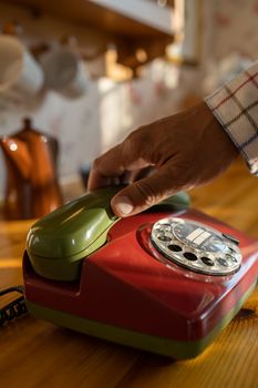 Close-up of a retro rotary phone with a hand reaching for the receiver, evoking nostalgia.