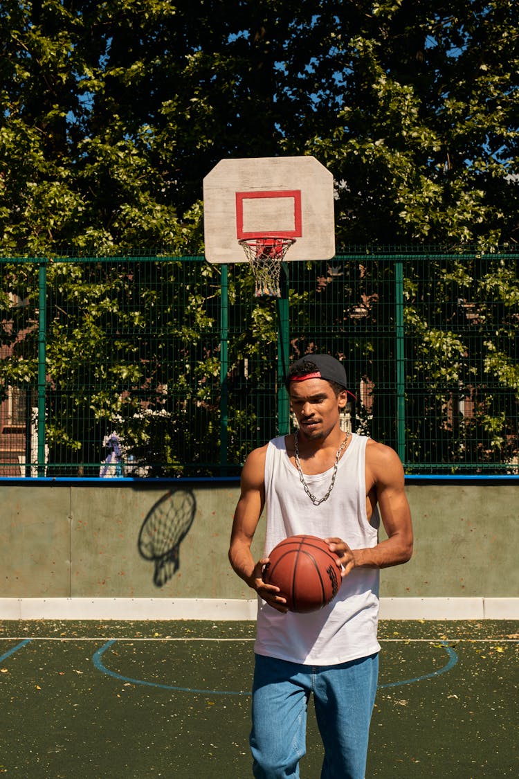 A Man Holding A Ball In The Basketball Court