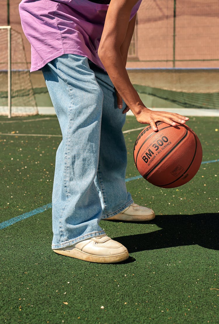 Person In Denim Jeans Dribbling The Ball