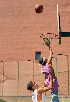 Two teenagers playing an intense game of basketball outdoors on a sunny day.