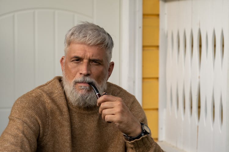 Elderly Man Sitting On Porch With Pipe