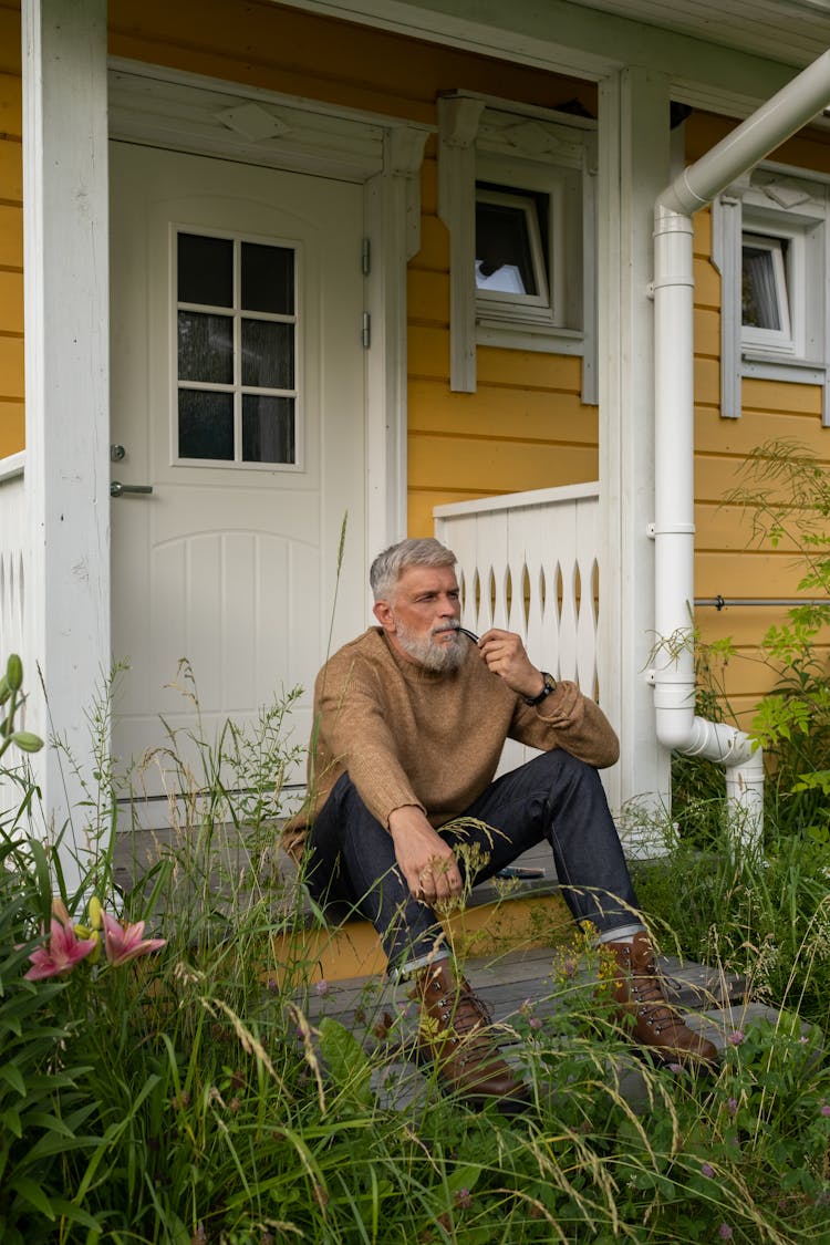 Elderly Man Sitting On Porch Holding Pipe