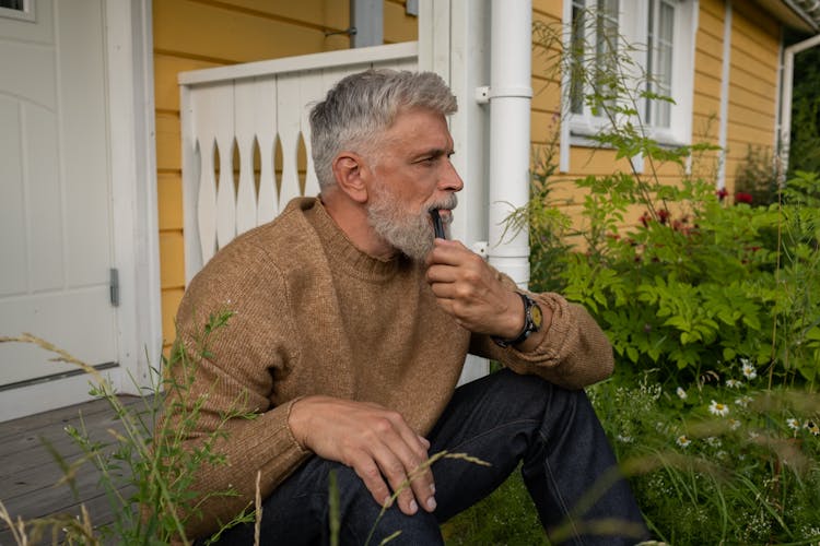 Elderly Man Sitting On Porch With Pipe