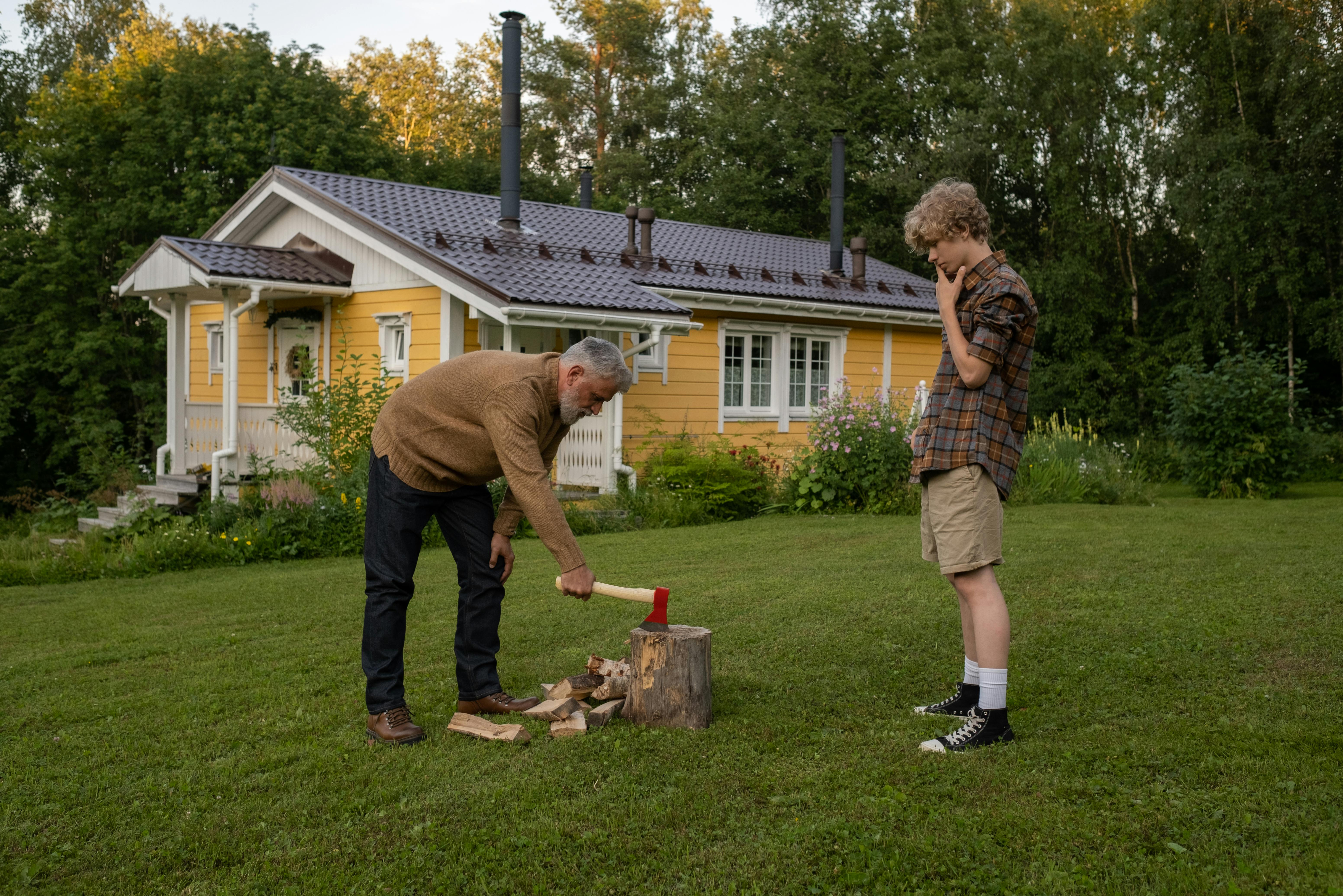 grandfather chopping wood and grandson watching