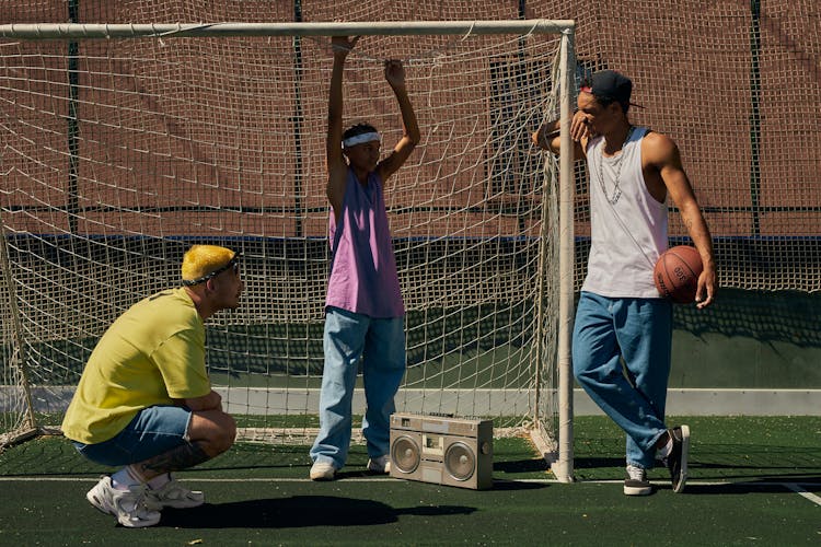 Group Of Friends With Old Boombox And Basketball Talking By The Soccer Goal