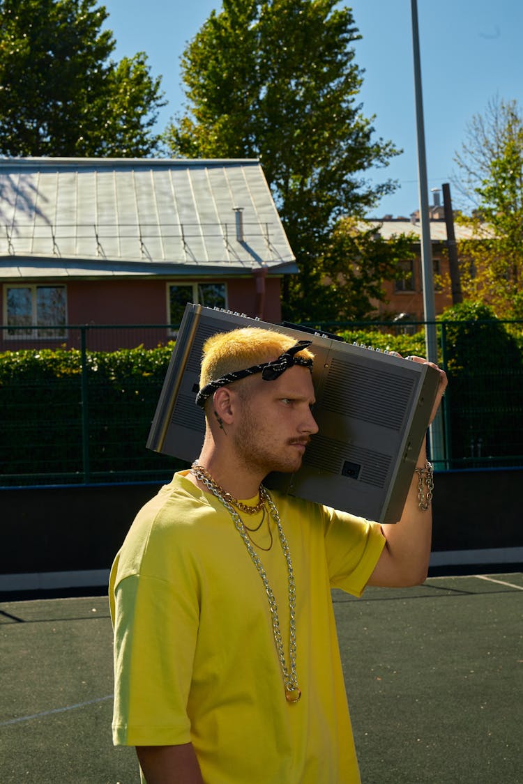 A Man In Yellow Shirt Carrying A Boombox