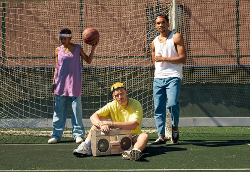 Casual urban fashion with a basketball and boombox on a sports field.