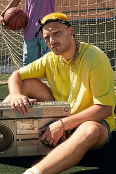 A trendy man with a boombox on a sports field, exuding retro vibes.