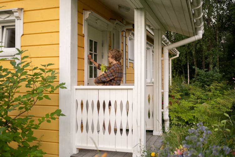 Teenage Boy With Stadning On Porch And Knocking On Door