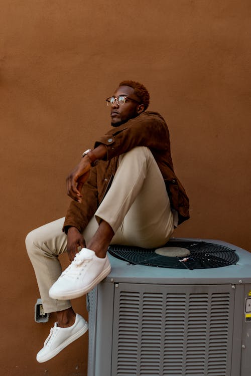 Man Sitting on Air Conditioning Unit