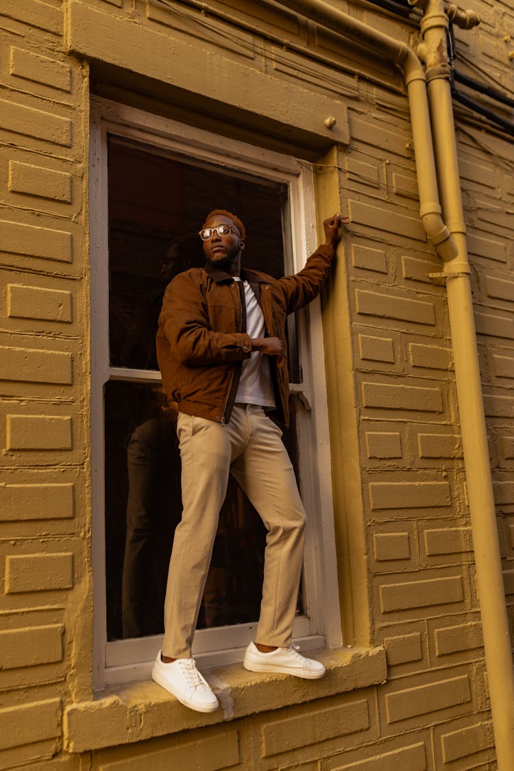 Man Wearing Glasses Standing On Windowsill