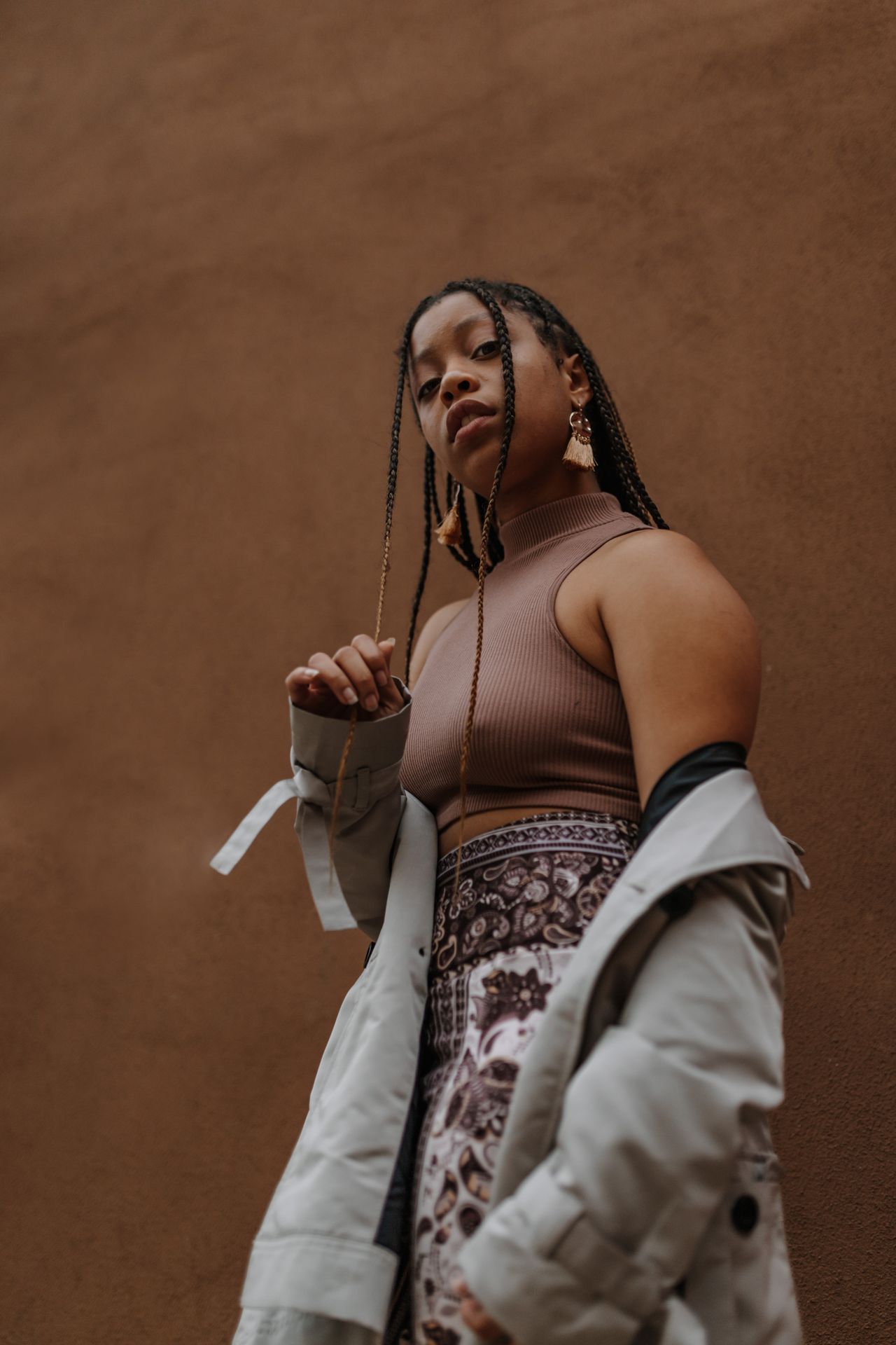 Woman with long box braids against a brown background