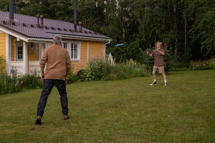 Grandfather And Grandson Playing Frisbee