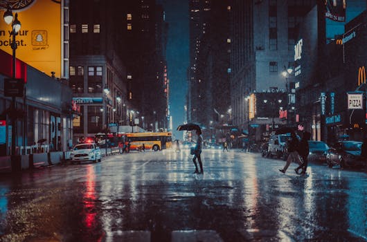 A rainy evening in New York City with people crossing a wet street under umbrellas.