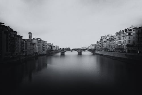 Grayscale Photo of City Buildings Near River