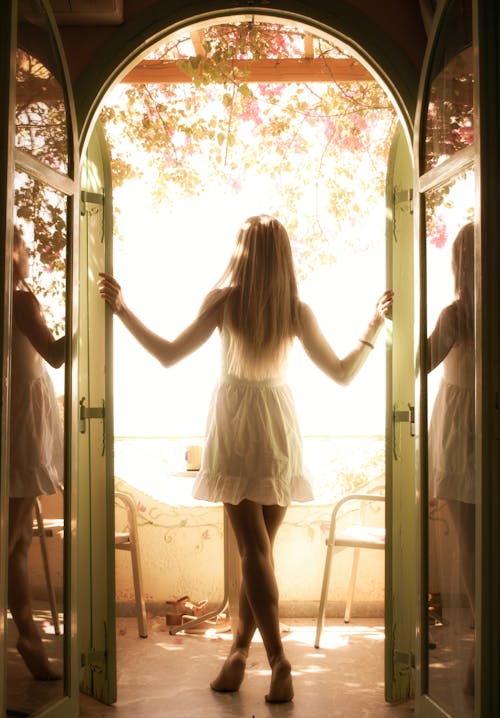 Free Woman Standing in White Dress in a Balcony Window Stock Photo
