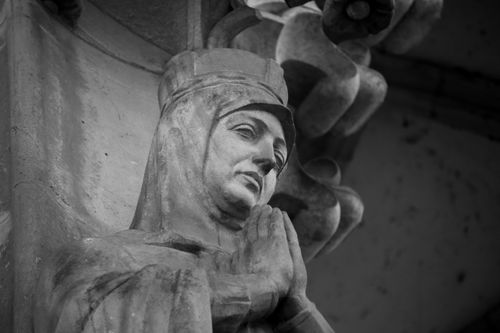 Free Grayscale image of a historic sculpture depicting a praying saint's serene expression. Stock Photo