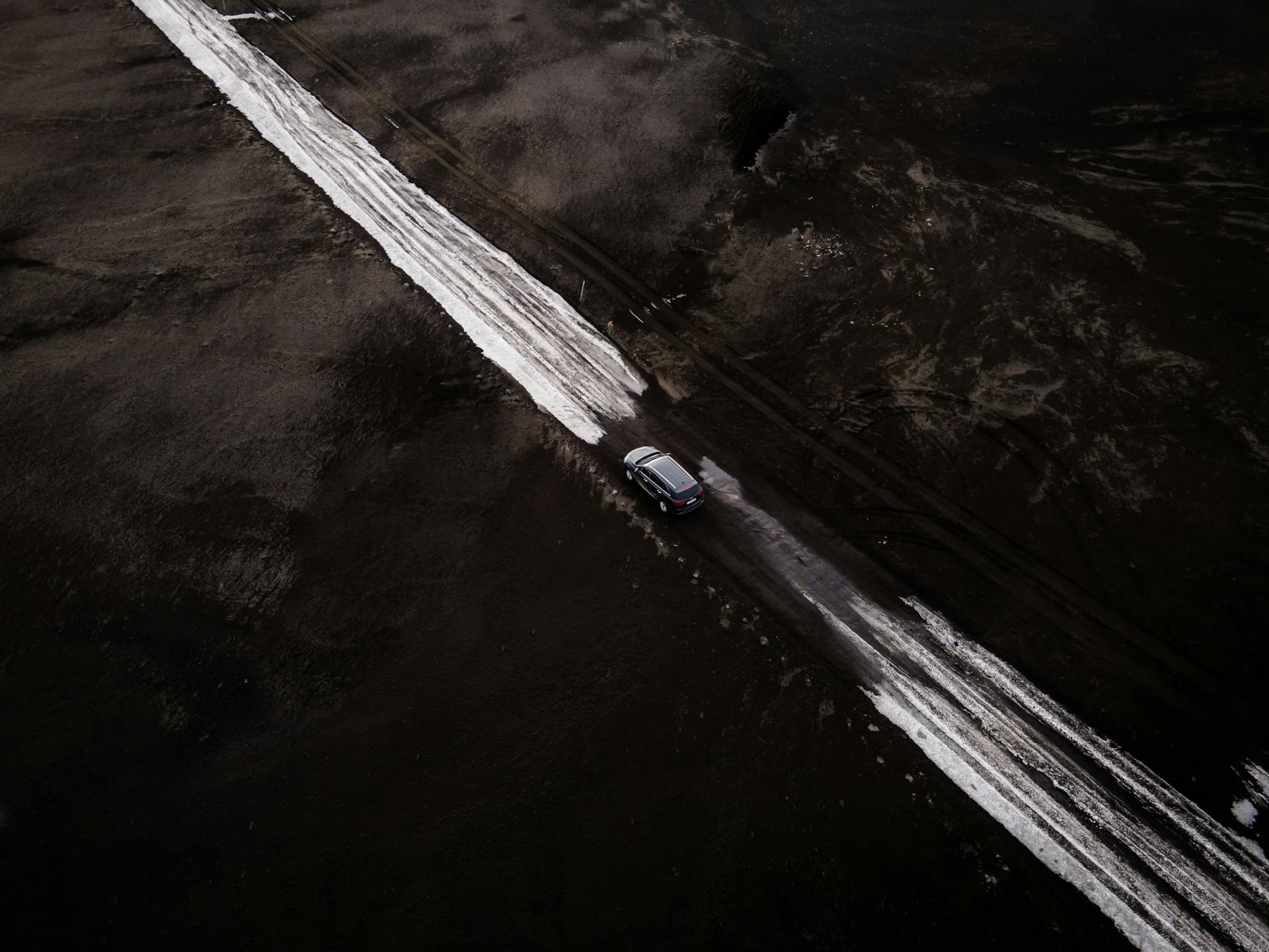 Car Moving on Road Covered with Snow Across Icelandic Landscape