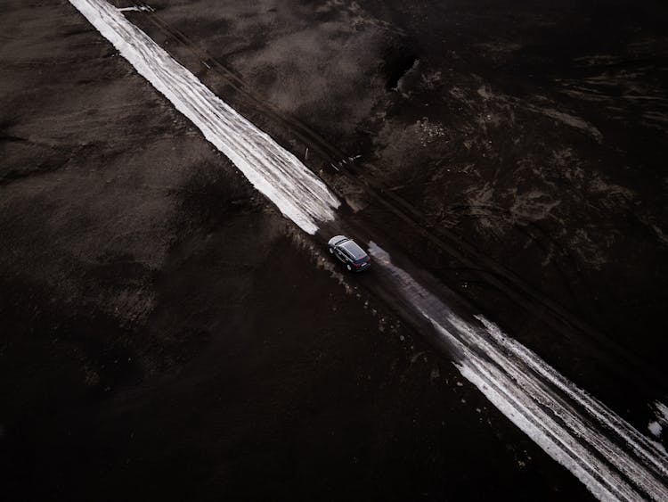 Car Moving On Road Covered With Snow Across Icelandic Landscape