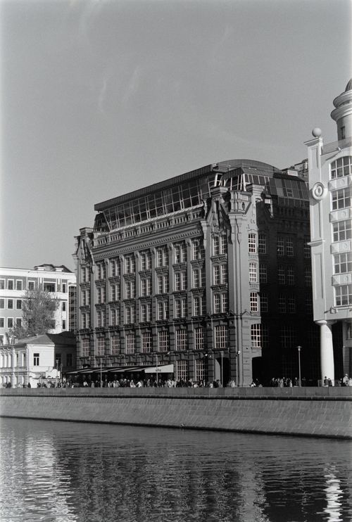 Free Striking grayscale photograph of classic urban buildings along a river embankment. Stock Photo