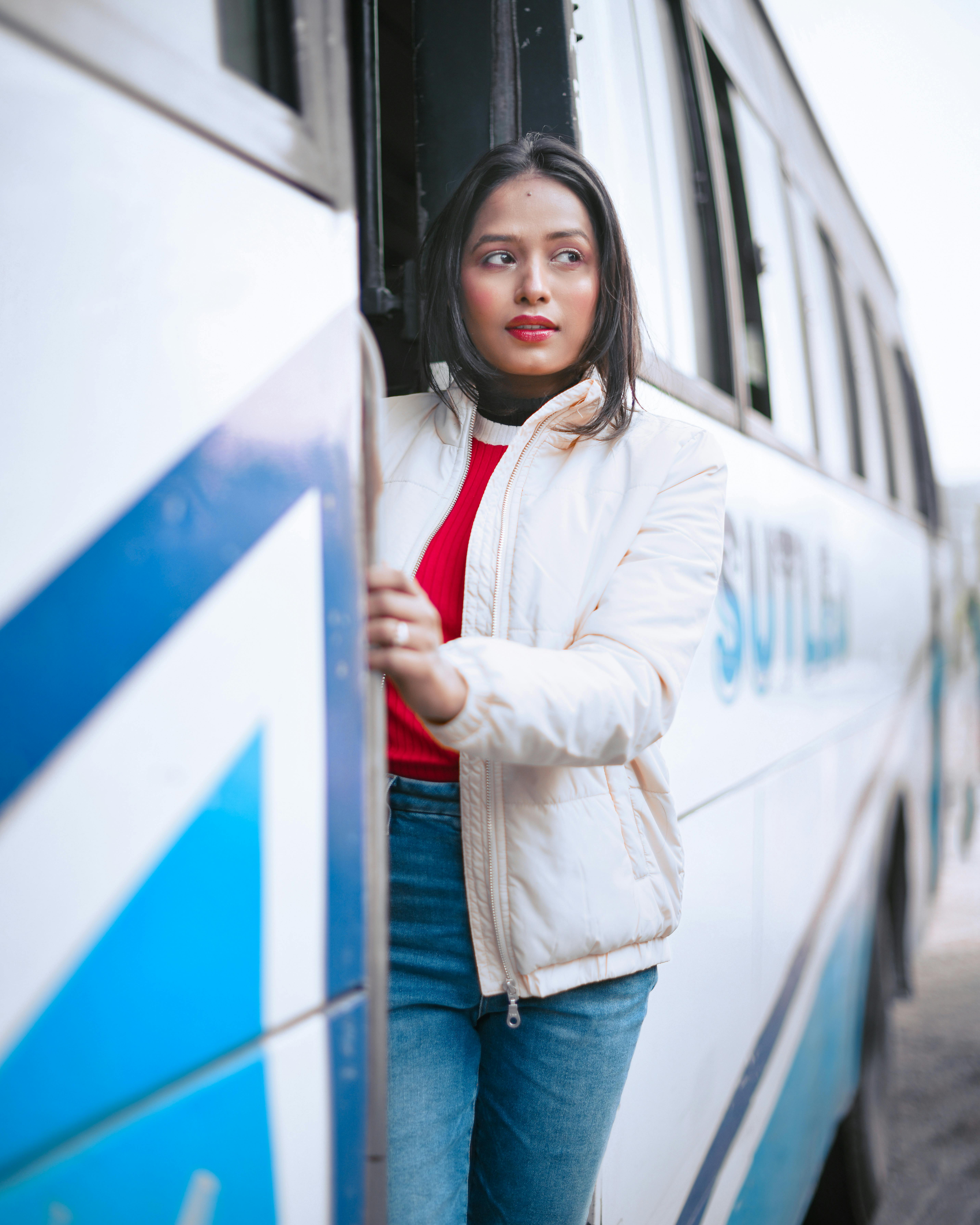 Asian woman standing at bus entrance, urban commuting moment.