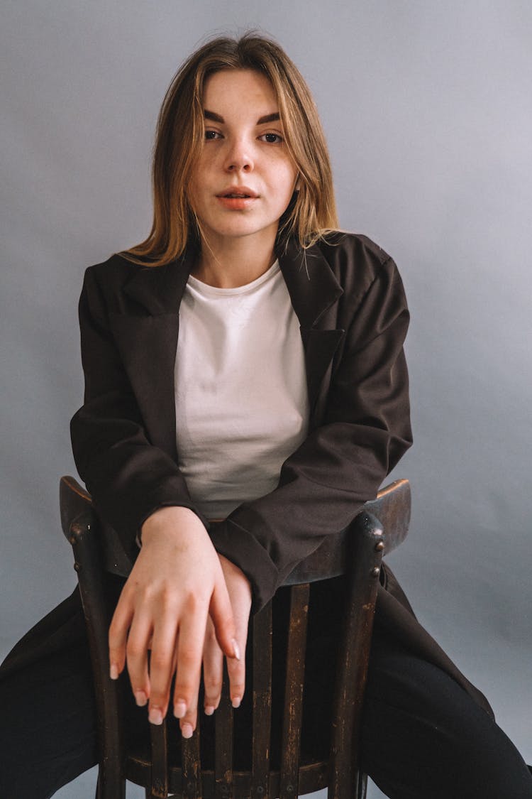 Portrait Of Woman Sitting On Chair In Studio