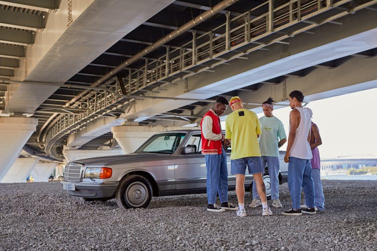 Group Of Young Men Doing Business Under The Bridge Next To A Silver Mercedes W124