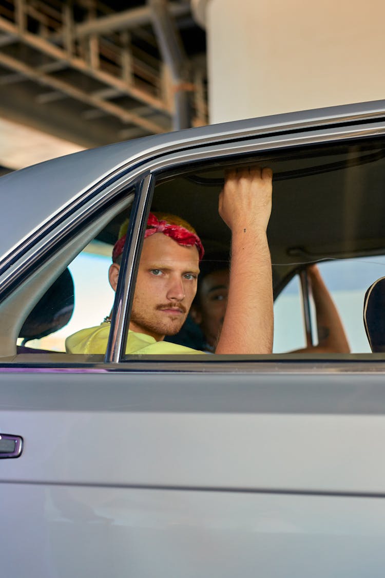 A Man In A Red Bandana Sitting At The Back Seat Of A Car