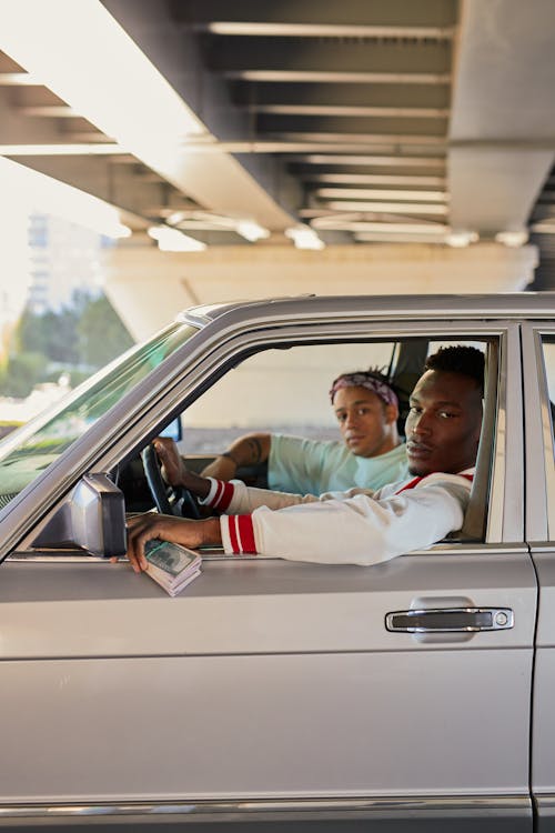 A Man Holding Cash while Driving a Car