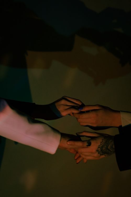 Free Two people holding hands in dark ambient lighting, symbolizing connection. Stock Photo