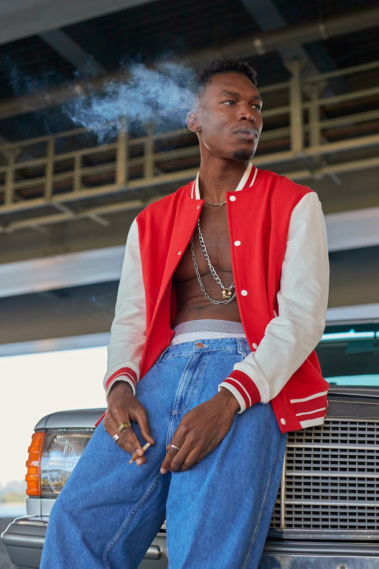 A Man Smoking While Leaning On The Car