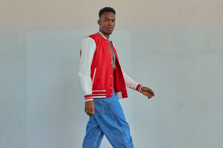 Man Wearing Red And White Jacket Walking Beside White Wall