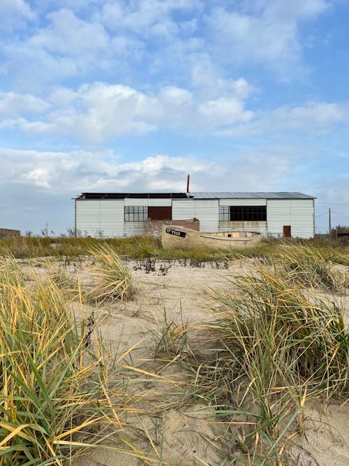 Grassy Beach With a Rowboat and a Boathouse in the Background