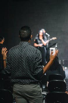 Man with raised hands worshipping during a live concert. Captures spiritual connection.