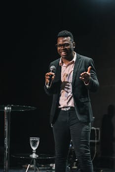 Smiling speaker in blazer and jeans gives a lively performance on stage.