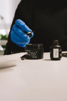 Close-up of a manicurist's gloved hand using brush and nail gloss.