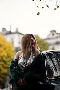 Fashionable woman in green fur coat and retro car setting during autumn in an urban landscape.