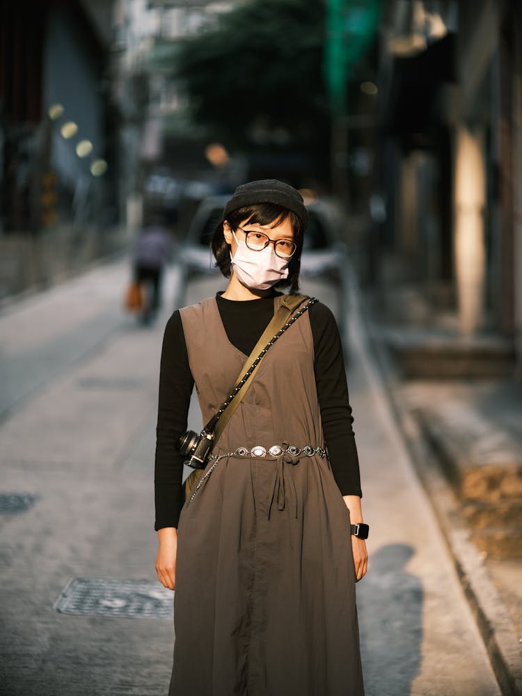 Asian Woman In Specs And Hat Wearing Face Mask In Street