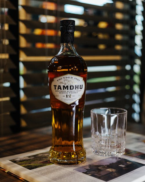 Clear Drinking Glass Beside a Bottle of Whisky