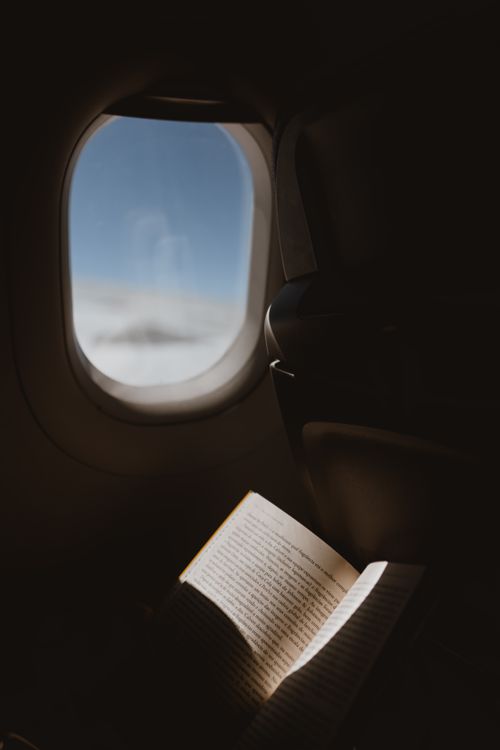 Free A peaceful moment reading by an airplane window with a view of the sky, capturing the essence of travel. Stock Photo