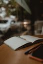 Open Notebook with Agenda Laying on Table by Window in Coffee Shop